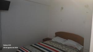 ein kleines Schlafzimmer mit einem Bett mit gestreifter Decke in der Unterkunft APARTAMENTO PRIMER PISO y cochera in Huaraz