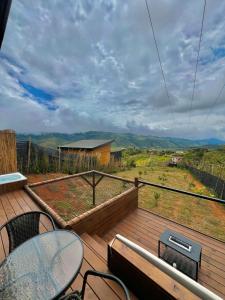 a deck with a table and chairs and a view at Entre Nubes Eco Hotel in El Queremal