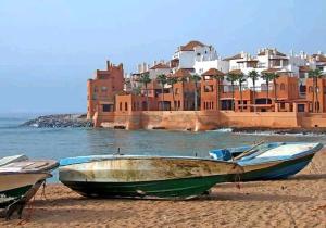 two boats sitting on the beach in front of a city at appartement plage Bouznika in Bouznika