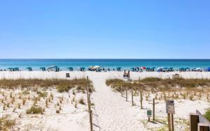 a beach with umbrellas and people on the beach at Ocean Breezes by Oversee 30A in Carillon Beach