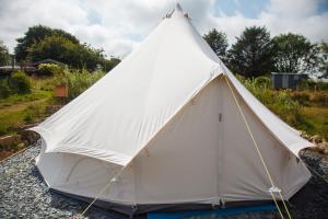 a white tent sitting on the rocks at Glamping Meadow Bell Tent in Stithians +20 photos