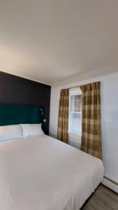 a bedroom with a large white bed and a window at Village Motel in Clinton