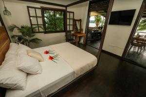 a bedroom with a white bed with flowers on it at Bocas Sunset Beach House in Bocas del Toro