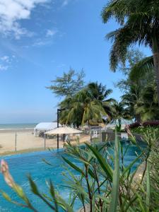 a swimming pool next to a beach with palm trees at TIMURBAY KUANTAN SEAVIEW PLUS By Timurbay Arza in Kuantan