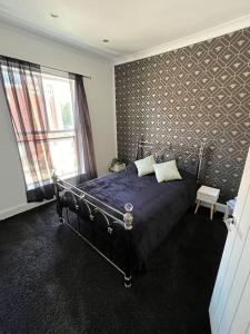 a bedroom with a bed with a blue comforter and a window at Central Two-three bedroom Beach town maisonette in Southsea