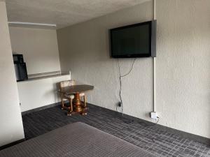a room with a table and a tv on the wall at Legend Motel in Des Moines