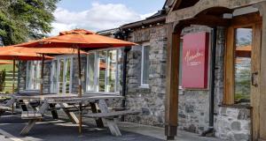 two picnic tables with umbrellas in front of a building at Castle Green Hotel In Kendal, BW Premier Collection in Kendal