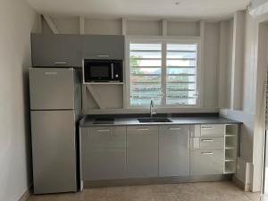 a kitchen with a refrigerator and a microwave at Mio Plage in Sainte-Anne