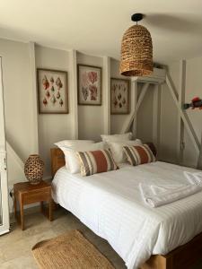 une chambre avec un grand lit blanc avec un lustre dans l'établissement Mio Plage, à Sainte-Anne 4 autres photos
