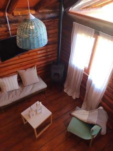 a living room with a couch and a table and windows at Cabaña Puesta del sol in Chascomús +42 photos