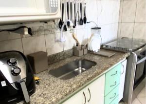 a kitchen counter with a sink and utensils at Apartamento recantoazul es Conforto Total a 50m do Mar Apartamento Recém-Reformado na Praia de Castelhanos, ES, para 7 Pessoas Aconchegante e Completo, com 3 Quartos e 1 Suíte in Anchieta