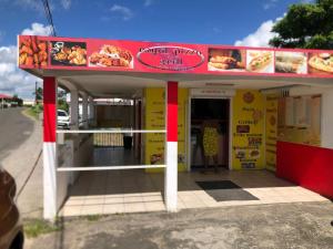 a fast food restaurant with a red and yellow building at Studio à la campagne in Le Moule
