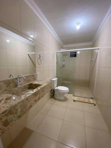 a bathroom with a toilet and a shower and a sink at Flat com 1 dormitório in Córrego da Forquiha