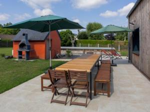 a wooden table and chairs with umbrellas on a patio at Maison familiale avec piscine chauffée, salle de jeux et grand jardin - 5 chambres, 15 couchages - FR-1-410-340 in Changé