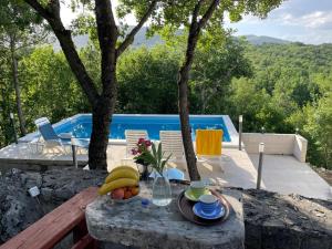 a bowl of fruit on a table next to a pool at Holiday house with a swimming pool Grubine, Zagora - 22263 in Krivodol