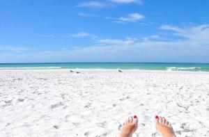 a person with their toes in the sand on the beach at Stunning Ocean-View Penthouse! Spacious, New, in Village, 20 steps to Best Beach! in Siesta Key