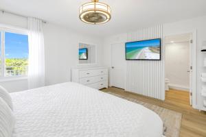 a white bedroom with a bed and a flat screen tv at Stunning Ocean-View Penthouse! Spacious, New, in Village, 20 steps to Best Beach! in Siesta Key
