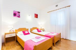 une chambre avec deux lits aux draps roses et blancs dans l'établissement Seaside family friendly house with a swimming pool Grscica, Korcula - 23487, à Blato 33 autres photos
