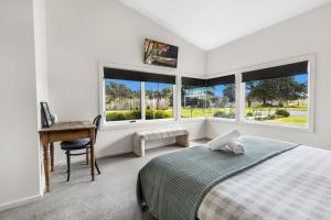 a bedroom with a bed and a desk and windows at Limestone Views in Swan Reach