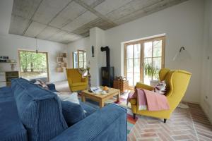 a living room with a blue couch and yellow chairs at Sąsny in Łajs