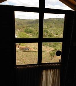 ein Fenster in einem Zimmer mit Blick auf ein Feld in der Unterkunft vistas del valle Cabaña in Valle Hermoso