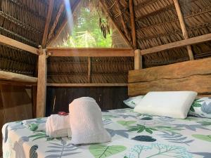 a bed in a thatched room with towels on it at Jungle Cabin - Satori Natural in Puerto Nariño
