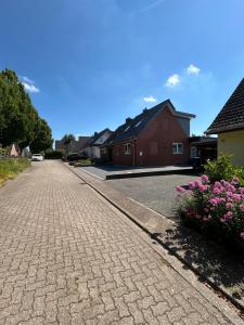 a cobblestone street with houses and pink flowers at Ferienhaus Kader in Eckernförde