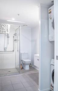 een witte badkamer met toilet en douche bij The Downtown - A Mount Maunganui Apartment in Mount Maunganui
