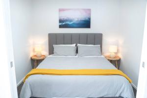 een slaapkamer met een groot bed met twee lampen bij The Downtown - A Mount Maunganui Apartment in Mount Maunganui