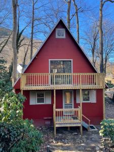 ein rotes Haus mit einer Terrasse im Wald in der Unterkunft Relaxing Creek Cabin in Canton