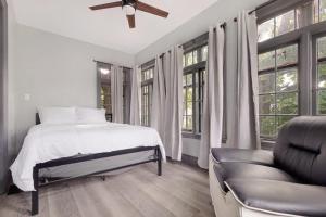 a bedroom with a bed and a chair and windows at Cozy 4BR 1BA close to the Falls in Niagara Falls