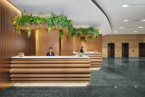 um lobby com duas pessoas atrás de um balcão com plantas em Nina Hotel Causeway Bay em Hong Kong