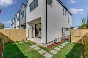 a white house with a fence and a yard at 2-bedroom ensuite, close to city, comfortable, accessible with own parking in Christchurch