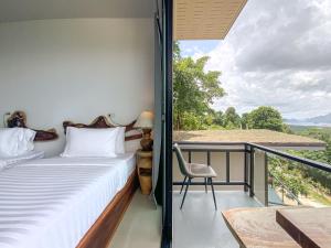 una camera da letto con balcone, letto e sedia di Samet Nangshe Goodview a Ban Met Nang Chi