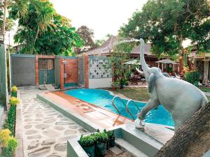 a statue of an elephant standing next to a swimming pool at Kamulyan Heritage Family in Yogyakarta