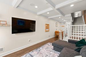 a living room with a couch and a tv on the wall at Federal Hill Luxury with Parking & Harbor View Rooftop in Fells Point