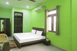 1 dormitorio con cama blanca y paredes verdes en Capital O A-one, en Manesar