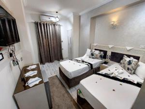 a hotel room with two beds and a mirror at Al Amir Palace Hotel in Sūhāj