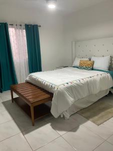 a bedroom with a bed with a bench and green curtains at Apartamento acogedor in Sabana Grande