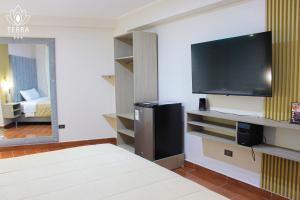 a living room with a tv and a room with a bed at Terra Premium Hotel in Huánuco