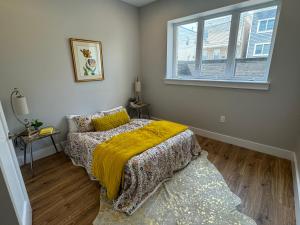 a bedroom with a bed with a yellow blanket and a window at Sunny Apt by the park Mins away from midtown New York in Jersey City