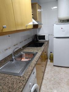 a kitchen with a sink and a white refrigerator at Galatea Arena in Arenales del Sol