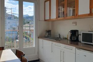 eine Küche mit weißen Schränken und einem großen Fenster in der Unterkunft Appartement proche centre-ville in Chamalières