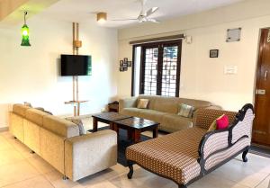 a living room with couches and a tv at SAFARI QUEST in Mysore +82 photos