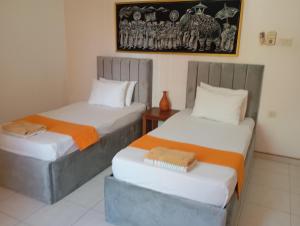 a room with two beds and a table and a picture at Larn's Villa Hotel & Apartment in Wadduwa