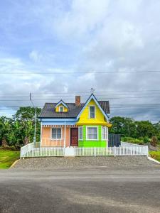 a small yellow and green house with a white fence at La Fortuna Up House in Fortuna