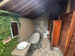 a bathroom with a toilet and a sink and a tub at Rumah Kayu Leke - Leke Guesthouse in Tegalalang