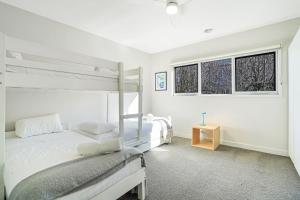 two beds in a white room with two windows at Port Retreat in Port Fairy