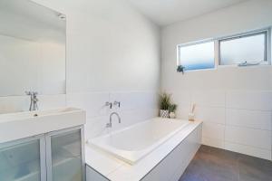 a white bathroom with a tub and a sink at Port Retreat in Port Fairy +10 photos