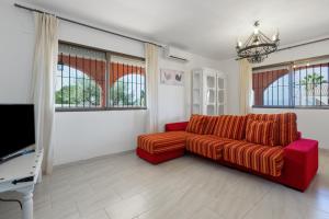 salon z czerwoną kanapą i telewizorem w obiekcie Casa los Manantiales w mieście Alhaurín de la Torre